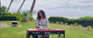 woman playing keyboard outdoors by the ocean